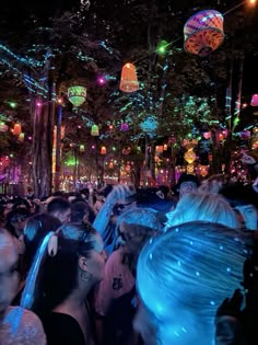 a large group of people standing in the middle of a park at night with lights on them