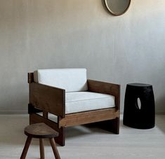 a chair and stool in a room with a clock on the wall behind it,