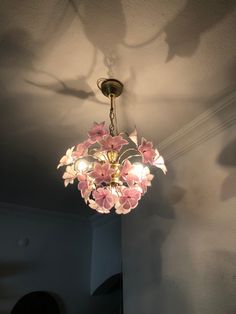 a chandelier with pink flowers hanging from it's ceiling in a room