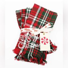 three red and green plaid christmas scarves with merry lettering on the front, one in white