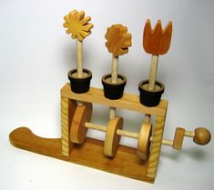 three potted plants are placed on top of a wooden stand with wheels and pegs