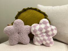 two knitted stars sitting on top of a white couch next to a green pillow