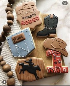 decorated cookies with cowboy themed decorations on a wooden board and bead necklace, along with beads