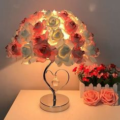 a lamp that is on top of a table with flowers in front of the lamp