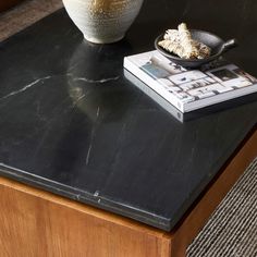 a black table with a white bowl and magazine on it next to a coffee table