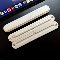 two white plastic handles sitting on top of a black table next to an apple laptop