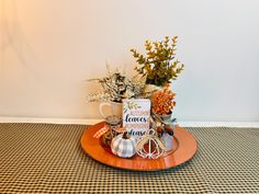 an orange plate topped with coffee mugs and other items on a checkered table cloth