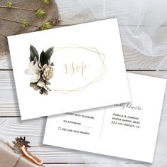 two white envelopes with flowers and greenery on them, next to a pair of scissors