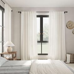 a bedroom with a bed, window and two clocks on the wall next to it