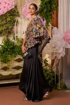 Black organza cape style kaftan with one shoulder neck, all over floral pattern, multi color sequin, cut dana and bead embroidery. Paired with flared pants with inserted pleated godet panels and gold toned halter neck padded blouse with all over daisy embroidery. - Aza Fashions Organza Dupatta With Cape Sleeves For Party, Party Organza Dupatta With Cape Sleeves, Evening Kaftan With Cape Sleeves For Eid, Elegant Party Dupatta Cape, Elegant Party Cape-shaped Dupatta, Elegant Party Cape Dupatta, Party Silk Kaftan With Sheer Dupatta, Silk Kaftan With Cape Sleeves For Evening, Festive Evening Dupatta In Cape Style