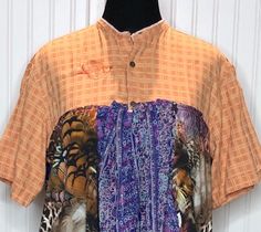 This beautiful women's shirt was upcycled using a mens orange  cotton check shirt and soft polyester blouses to fashion this easy fitting 2X shirt.  The main body is a light weight cotton orange with subtle check pattern shirt with top three button closure.  The bottom of the shirt is several polyester blouses in purple and orange patterns. This is a pop over style, but the three buttons make it easy on and off.  The sleeves half sleeve length is perfect for a stylish fit.  The two side pockets are made from one of the purple blouses. The top has been embroidered with the Little Bird Products signature bird in orange thread.   All seams are serged for longevity.  This style is flattering to any body type and the shirts used are washable and easy care.  Please review the measurements below Relaxed Fit Collared Patchwork Shirt, Casual Tunic Shirt For Summer, Casual Summer Tunic Shirt, Summer Casual Tunic Shirt, Cotton Tunic Shirt For Summer, Relaxed Fit Short Sleeve Patchwork Blouse, Oversized Patchwork Short Sleeve Tops, Summer Bohemian Tunic Shirt, Spring Short Sleeve Patchwork Shirt