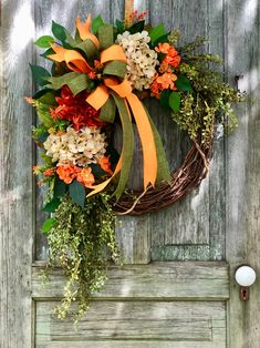 a wreath with orange and white flowers hanging on a door