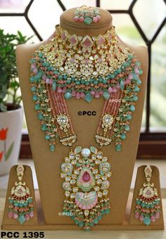 an elaborate necklace and earring set on display in front of a potted plant