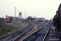 an old train yard with railroad tracks running parallel to each other and buildings in the background