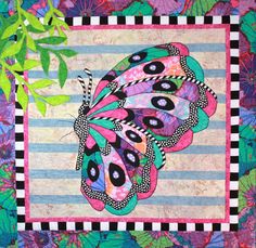 a colorful quilt with a butterfly on it's back and green leaves in the background