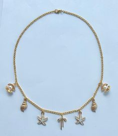 The Coastal Bow Charm Necklace is the perfect addition to any outfit, effortlessly elevating your style with its charming and beautiful design. The delicate bow charm at the center, surrounded by the cute white starfish, the gold conch shells, and the clam shells with their gorgeous pearls, creates a stunning piece that complements any summer look.  Pair this necklace with a breezy sundress for a day out, or add it to a t-shirt over your swimsuit for a casual look. The necklace also looks great with a simple tank top and denim shorts, sprucing up your everyday attire. Ideal for summer and beach outings, the Coastal Bow Charm Necklace captures the essence of the seaside with its nautical-inspired charms. Perfect for a beach party or a seaside brunch! The necklace is 18 inches long and handm Ocean-inspired Jewelry With Lobster Clasp For Vacation, Beach Jewelry With Charms In Ocean-inspired Style, Ocean-inspired Jewelry For Vacation With Lobster Clasp, Ocean-inspired Jewelry With Charms For Beach, Ocean-inspired Beach Jewelry With Charms, Gold Starfish Charm Necklace For Beach Season, Gold Beachy Necklace With Starfish Charm, Starfish Charm Necklace For Beach Vacation, Starfish Charm Necklace For Beach Season Vacation