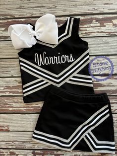 a cheerleader outfit with a bow on the front and side, sitting on top of a wooden floor