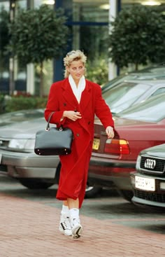 a woman in a red suit and white shirt is walking down the street with her handbag