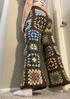 a woman standing in front of a door wearing crocheted pants