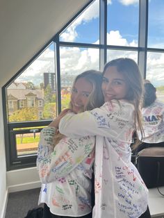 two girls hugging each other in front of a window with writing all over them on it