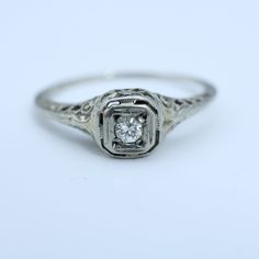 an old - fashioned diamond ring with filigrees on the sides, set in white gold