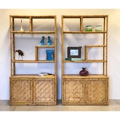 two bamboo shelves with baskets and vases on them in front of a white wall