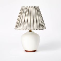 a white table lamp with a black and white checkered shade on the top, against a white background