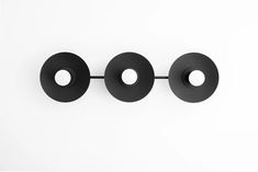 three black circles on a white wall with two holes in the middle and one hole at the end