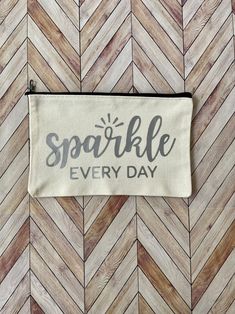 a small zipper bag with the words sparkle every day printed on it, sitting on a wood floor