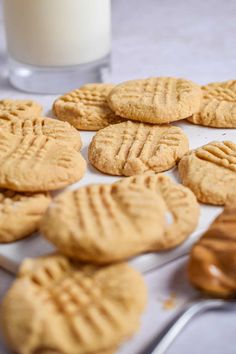 peanut butter cookies on a plate with a glass of milk and spoons next to it