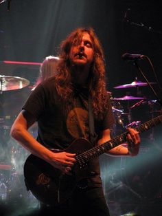 a man with long hair playing an electric guitar