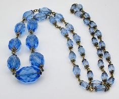 Up for sale is a vintage 1920-30s era Art Deco necklace of blue, faceted melon glass beads. MARKINGS: None but very conducive of vintage Czech jewelry. DESCRIPTION: The necklace is strung in the graduated bead style. It measures 16 1/2" from the top of the necklace to the bottom and has no clasp. It is the style that easily slips over the head. There are gilded brass findings between each bead. The largest bead measures approximately 21 x 14mm and the smallest one measures 6 x 13mm. It weighs in at 2.1 ounces or 60 grams. CONDITION: The condition is very good considering the age. I need not see any chips or nicks in any of the beads. There is some wear to metal findings and could benefit from a gentle polishing. DON'T SEE WHAT YOU'RE LOOKING FOR HERE? CUT AND PASTE THE LINK INTO YOUR BROWS Vintage Czech Glass Oval Beaded Necklace, Blue Faceted Oval Beads Jewelry, Vintage Glass Necklace With Oval Beads, Vintage Blue Oval Bead Necklace, Vintage Glass Necklaces With Oval Beads, Vintage Glass Beaded Necklaces With Oval Beads, Vintage Blue Necklace With Oval Beads, Vintage Blue Glass Necklace, Vintage Blue Glass Jewelry