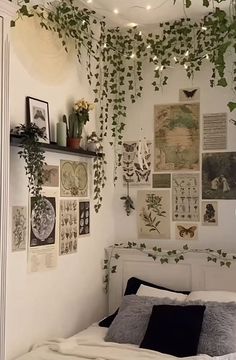 a bedroom with lots of plants hanging from the ceiling and pictures on the wall above it