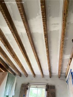 an unfinished room with exposed wood beams and a window in the center, along with other construction materials on the walls