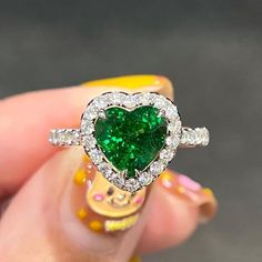 a heart shaped green diamond ring in someone's hand