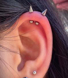 an ear with three different piercings attached to the side of it, and two smaller ones