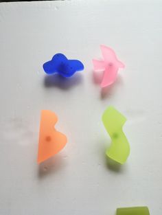 four different colored plastic shapes on a white surface