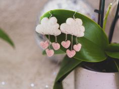 the earrings are made out of wool and have hearts hanging from them, along with pearls