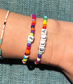 two bracelets with letters that spell out the word ella on them, sitting on a person's arm