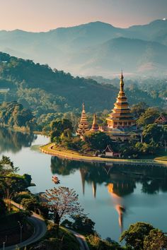 an aerial view of a lake and pagodas in the distance with mountains in the background