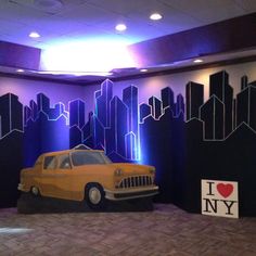 a yellow car is parked in front of a wall with cityscapes painted on it