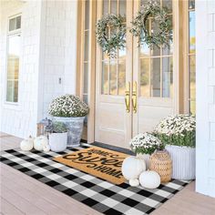 two potted plants are sitting on the front porch door mat that says welcome home