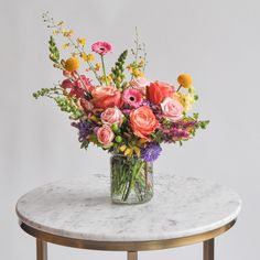 a glass vase filled with colorful flowers on top of a marble table