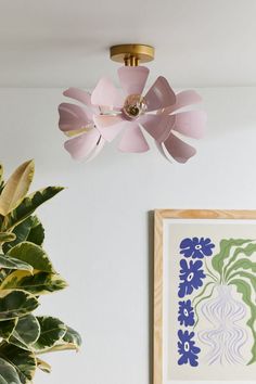 a pink ceiling fan hanging from the ceiling next to a potted plant on a table