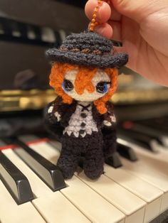 a tiny doll is sitting on top of a piano keys and wearing a black hat