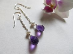 A pair of beautiful matched faceted Amethyst 12 by 8 mm briolettes are topped with a sweet semi round Freshwater Pearl and hung on long Sterling Silver chains. An elegant and dainty pair for those very special moments. Marianne got a pair for Christmas in Green Aventurine and they are destined to be a favorite. Amethyst is the official birthstone of February. Amethyst crystals grow on the inside surface of agate geodes. Amethyst ranges in color from deep purple to pale lavender depending on the Purple Briolette Earrings For Wedding, Briolette Earrings, Silver Chain Earrings, Earrings Pearl, June Birthstone, June Birth Stone, Chain Earrings, Green Aventurine, Amethyst Crystal