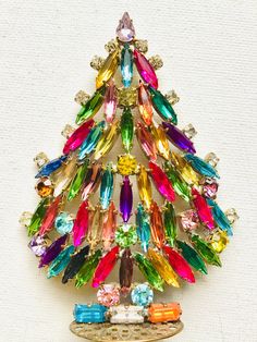 a multicolored christmas tree brooch sitting on top of a table