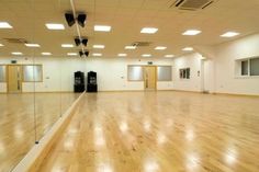 an empty room with hard wood floors and mirrors