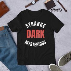 Strange dark and mysterious, Mr. Ballen Tell Me A Bedtime Story, MrBallen Merch, Mr. Ballen Merch, Tiktok Mr. Ballen, Strange Dark Mysterious, Short-sleeve unisex t-shirt This t-shirt is everything you've dreamed of and more. It feels soft and lightweight, with the right amount of stretch. It's comfortable and flattering for all.  * 100% combed and ring-spun cotton (Heather colors contain polyester) * Fabric weight: 4.2 oz/yd² (142 g/m²) * Pre-shrunk fabric * Side-seamed construction * Shoulder- Black Fandom T-shirt For Halloween, Black Letter Print T-shirt For Fan Conventions, Black Fandom T-shirt With Letter Print, Themed Black T-shirt With Letter Print, Themed Streetwear T-shirt With Letter Print, Black Horror T-shirt With Letter Print, Themed Letter Print T-shirt For Streetwear, Fandom T-shirt With Letter Print For Fan Conventions, Themed Black T-shirt For Fan Conventions