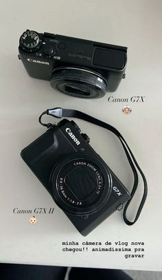 a camera sitting on top of a white table next to a black bag with the word canon written below it